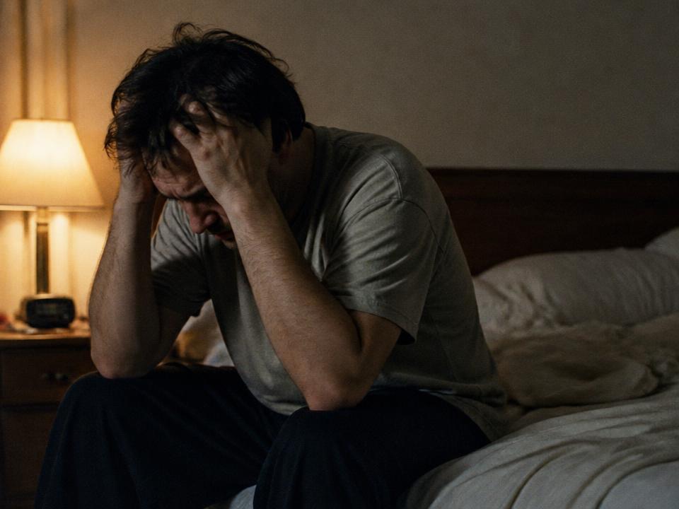 Homem acordado à noite, com as mãos no cabelo, sinal de estresse